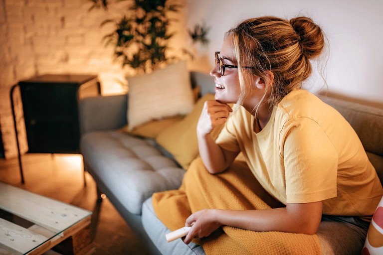 Frau lachen Fernbedienung Sofa